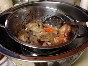 Straining the chunks of veg and bones.