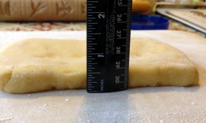 1/2 inch thick or a wee bit less. Depends on your dough texture and how hard you press down.